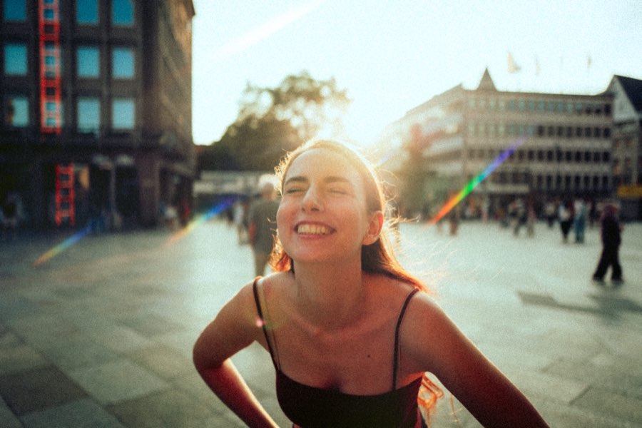 Smiling woman leaning forward on a city square in warm backlight