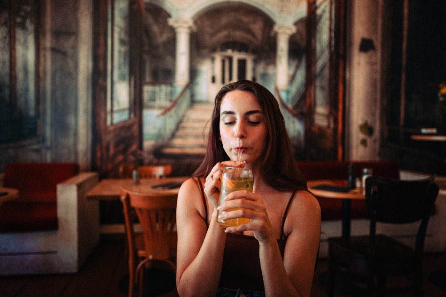 Woman sipping a drink in a café with a mural behind her