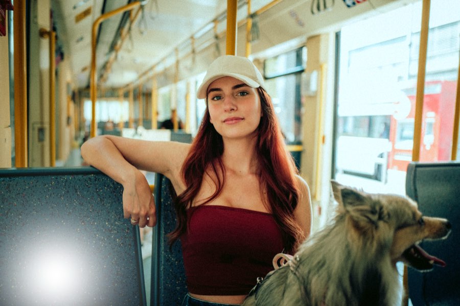 Woman in a cap sitting on a tram with a dog beside her