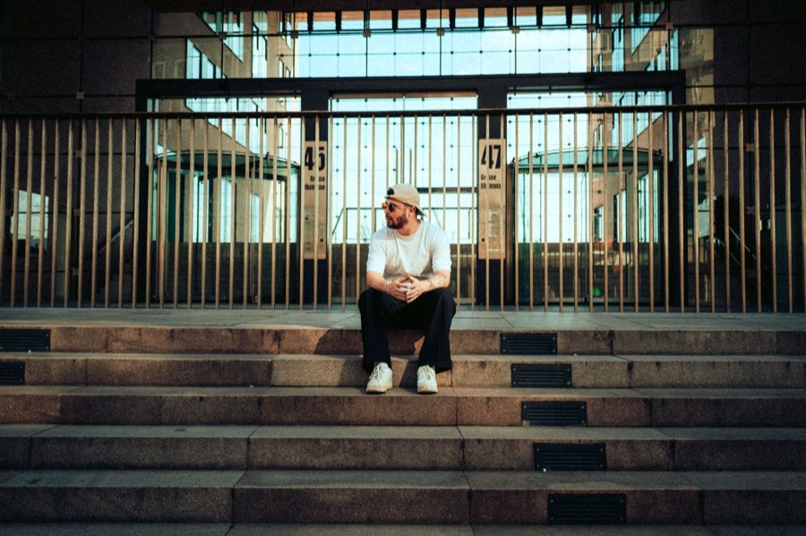Man sitting alone on wide stone steps in front of a glass building