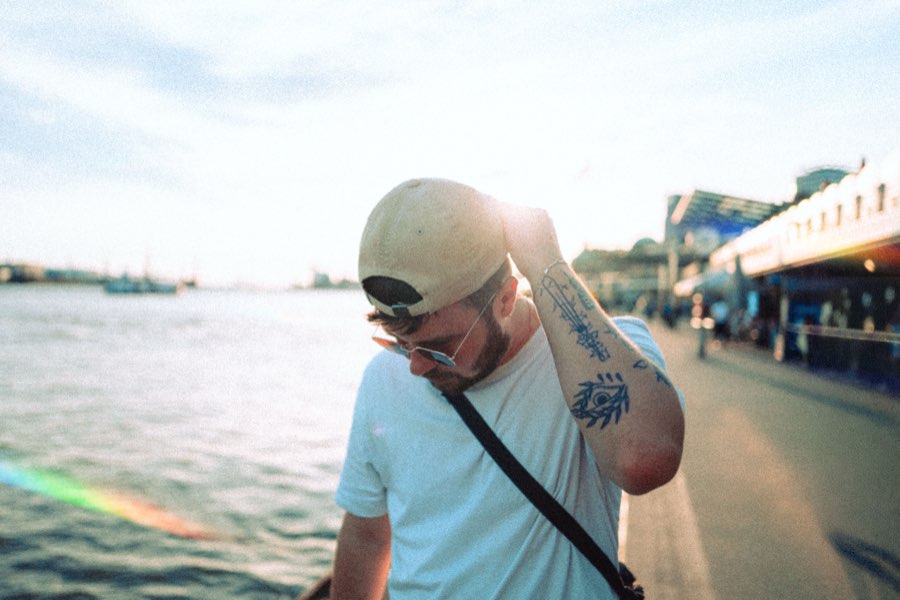 Man in a cap walking along the riverside, smiling down