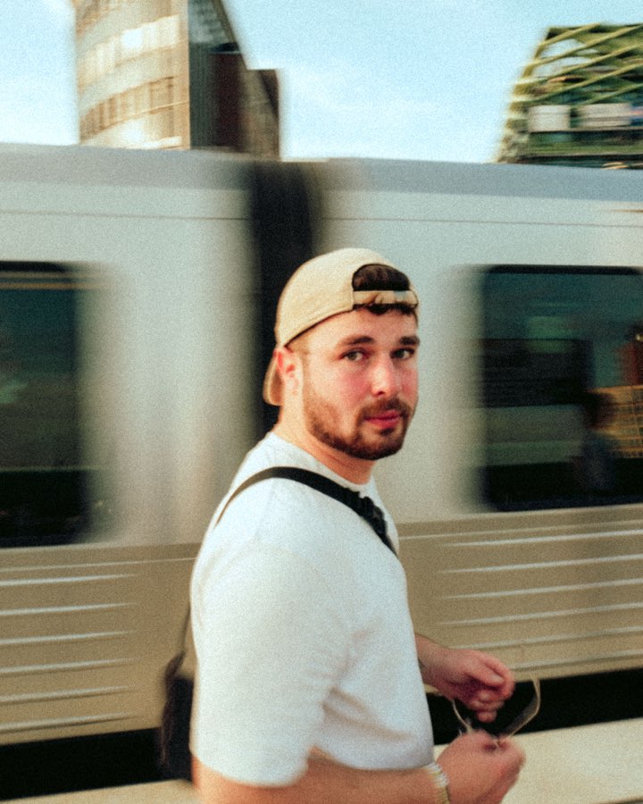 Man in a cap looking back over his shoulder in front of a passing train