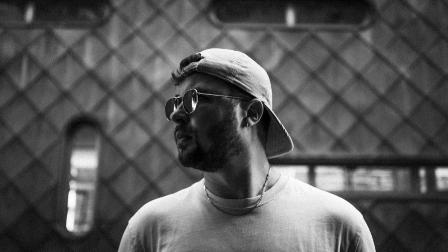 Black and white portrait of a man in a backwards cap and sunglasses