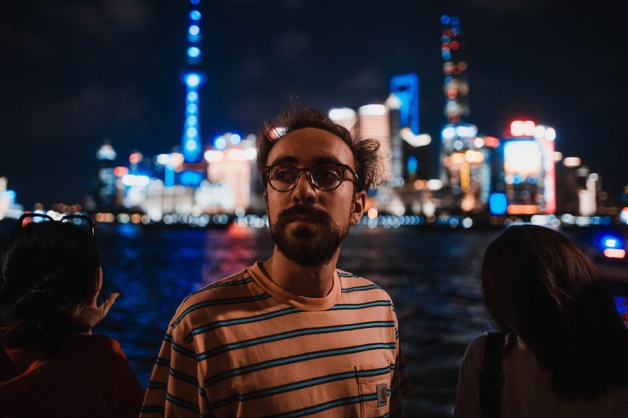 Man in a striped shirt in front of an illuminated city skyline at night