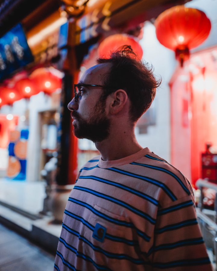 Man in a striped shirt in a street hung with red paper lanterns