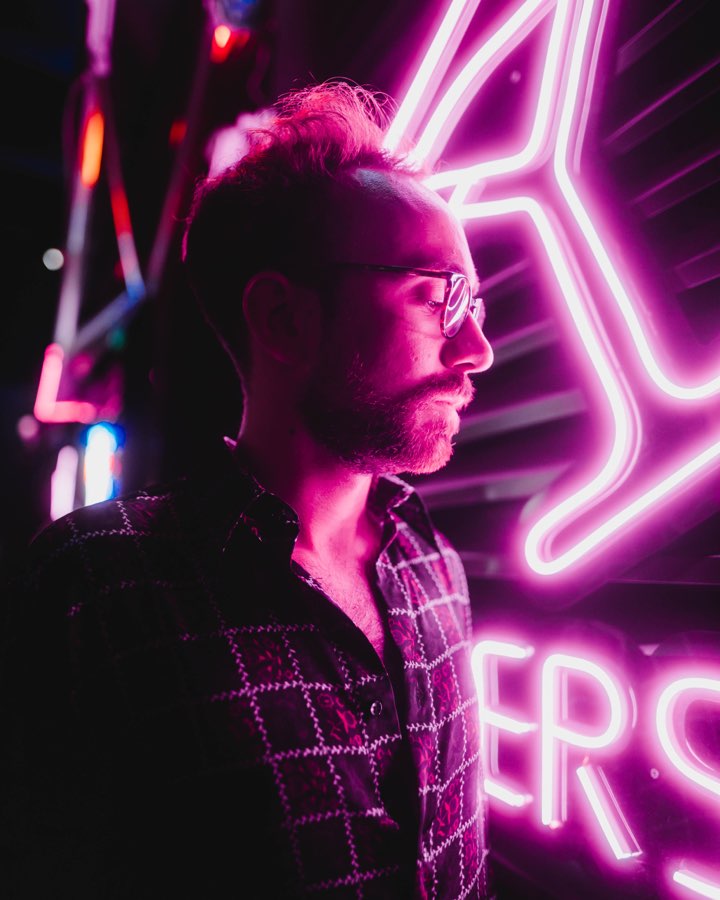 Profile of a man with glasses in pink neon light