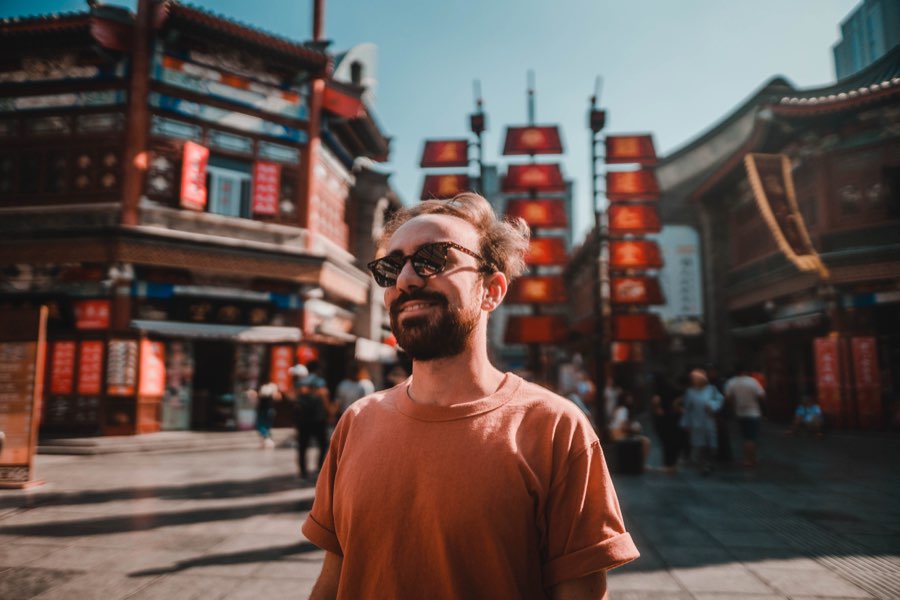 Smiling man in an orange T-shirt on a street with red lanterns