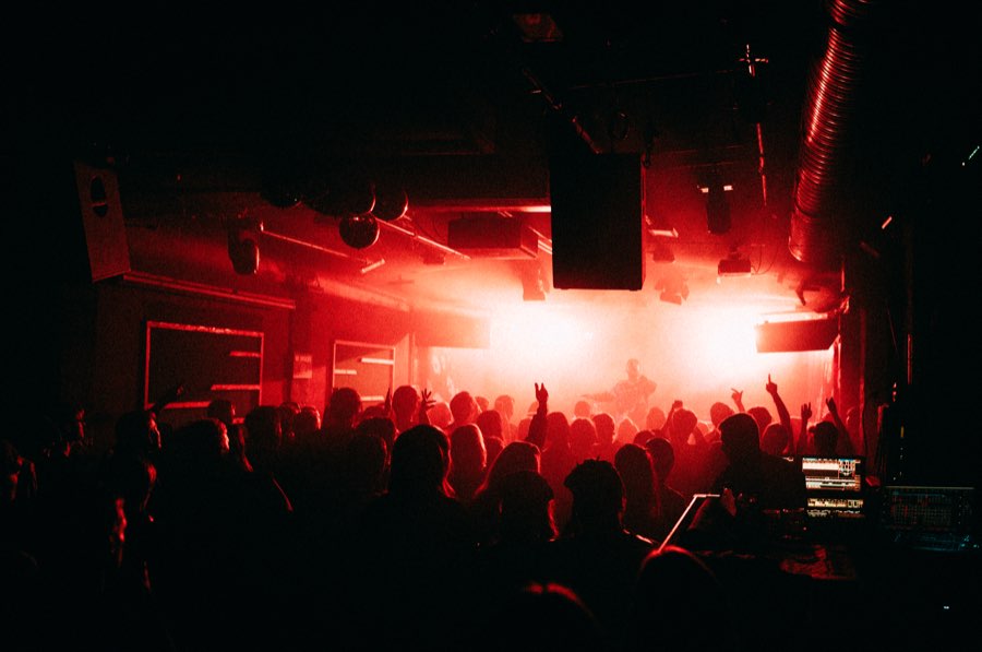 Crowd with raised hands in front of a stage flooded with red light