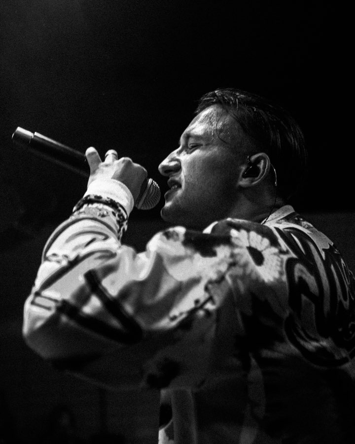 Black and white close-up of a performer rapping into a microphone in profile