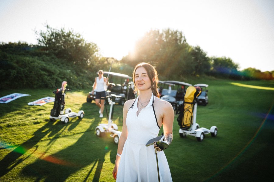 Smiling woman in a white dress on a golf course at sunset