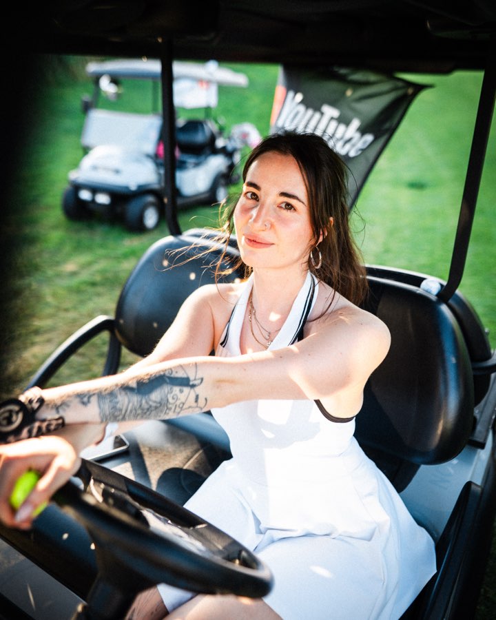 Woman with a tattooed arm at the wheel of a golf cart