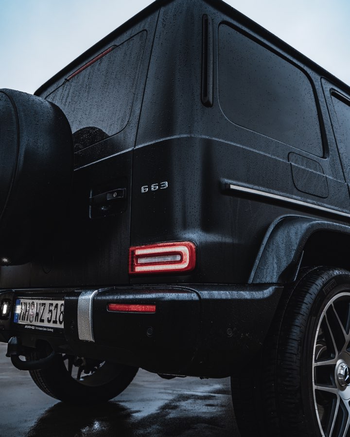 Rear of a matte black Mercedes G 63 on a wet street