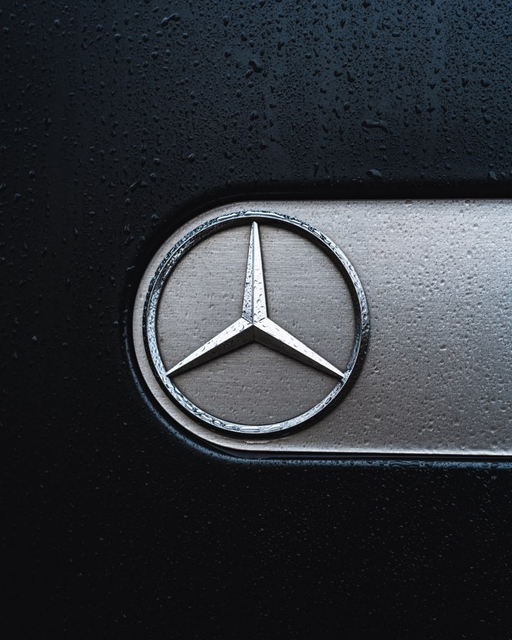 Mercedes star emblem on a wet black surface