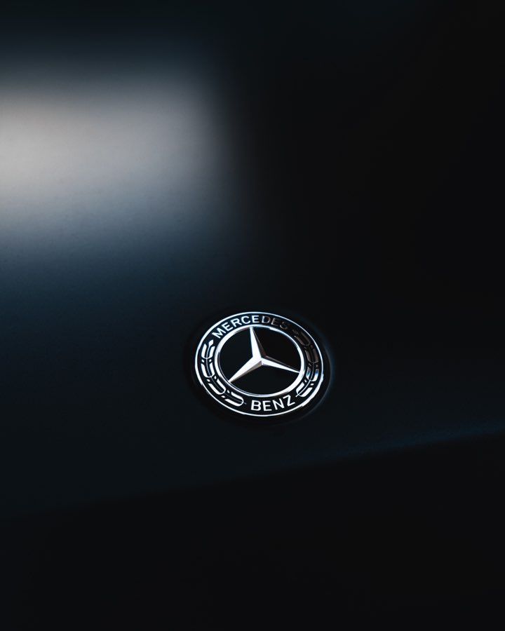 Mercedes-Benz badge on a black bonnet in soft light
