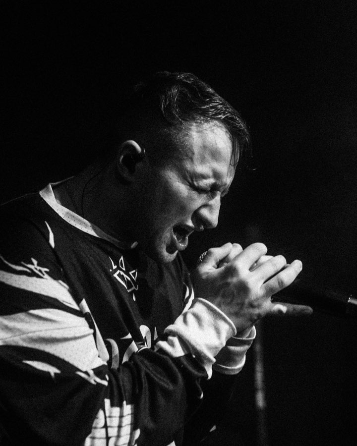 Black and white close-up of Navy singing with both hands around the microphone