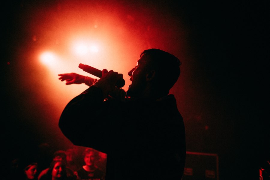 Silhouette of Navy rapping into the microphone in red backlight