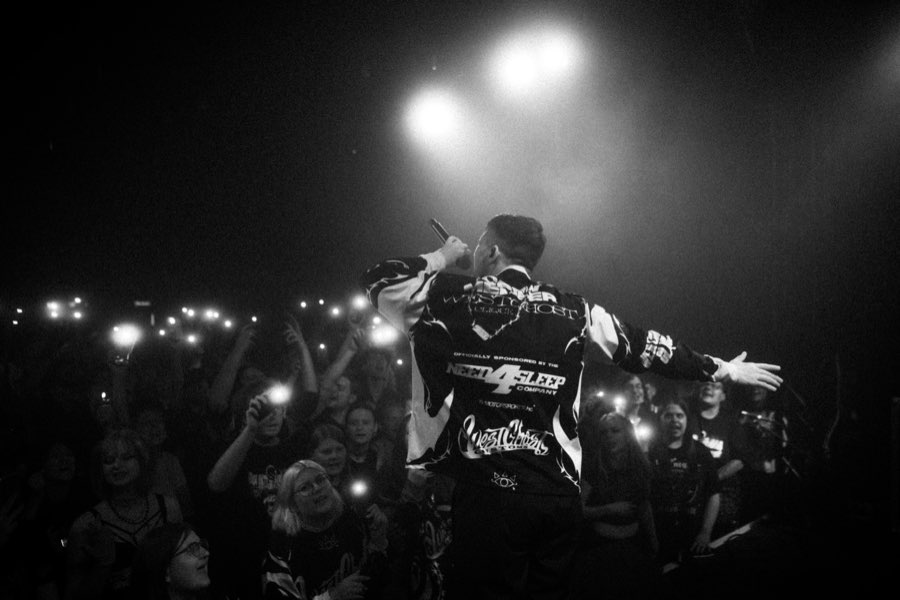 Black and white photo of Navy performing in front of a crowd holding up phone lights