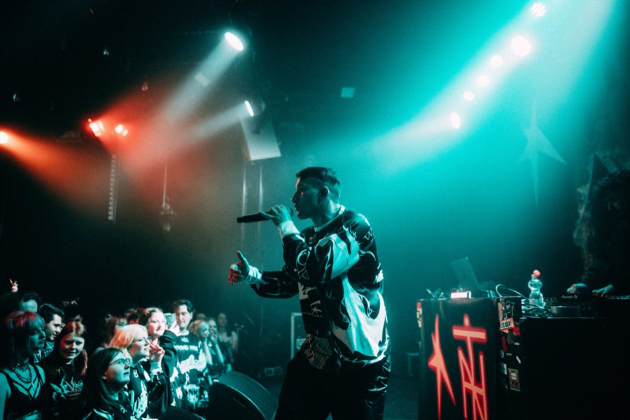 Navy performing in teal and red stage light in front of the crowd
