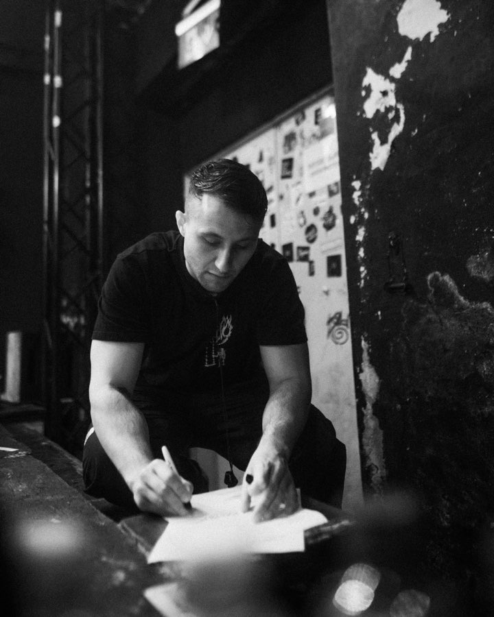 Black and white photo of Navy signing a poster backstage