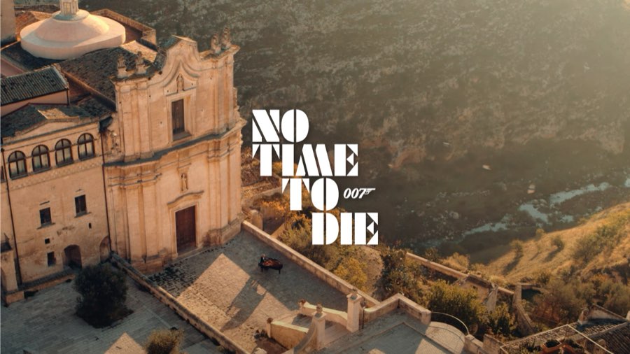 Aerial view of a historic hilltop town with the No Time To Die title
