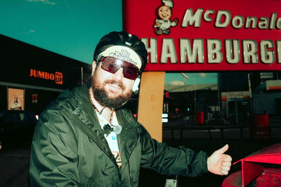 Bearded man in sunglasses giving a thumbs up in front of a McDonald's sign