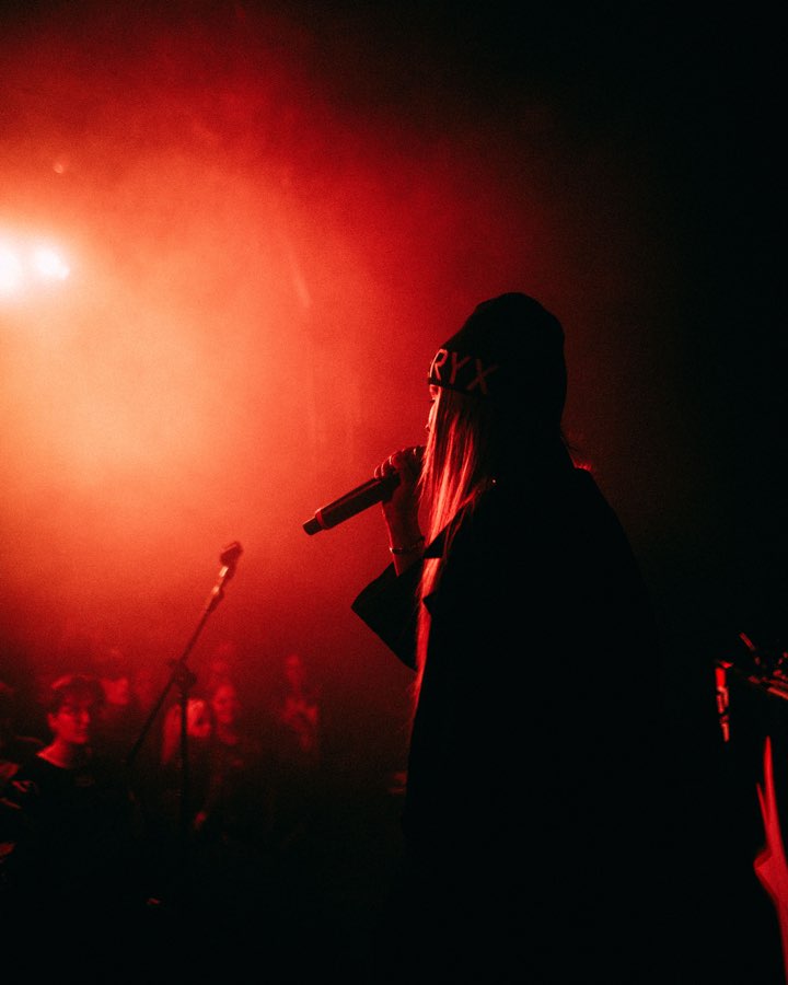 Singer in silhouette with a microphone, bathed in red stage light