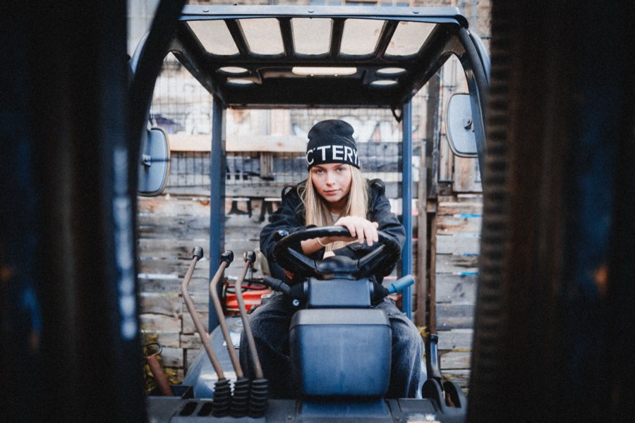 Woman in a beanie at the wheel of a forklift